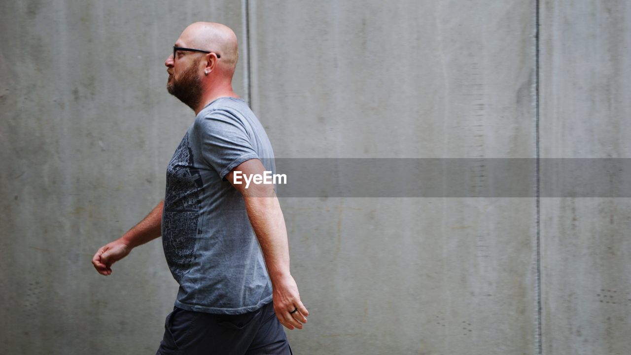 Man wearing eyeglasses walking against wall