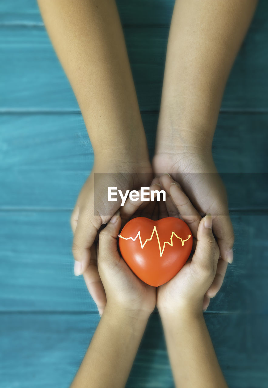 Cropped image of man holding heart shape on blue water