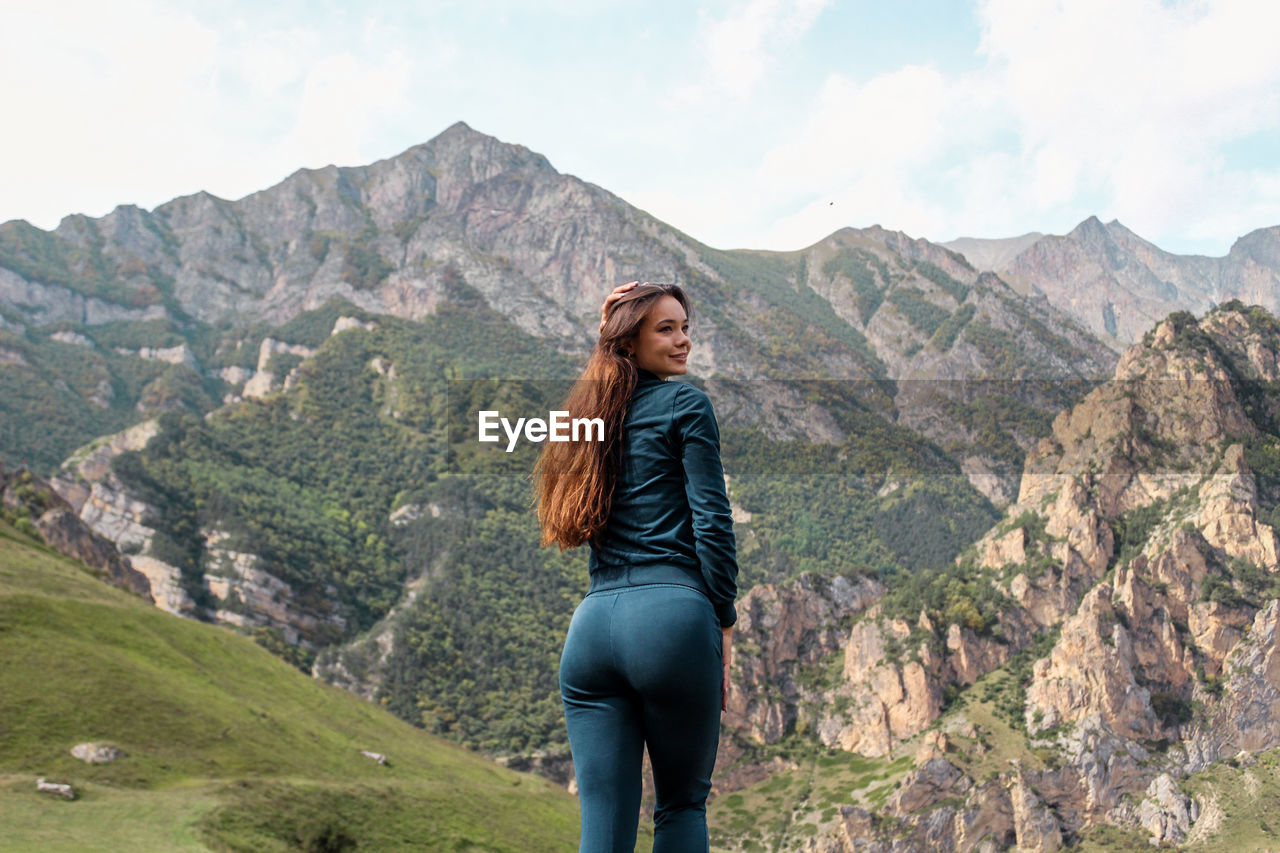 Beautiful woman standing against mountain range