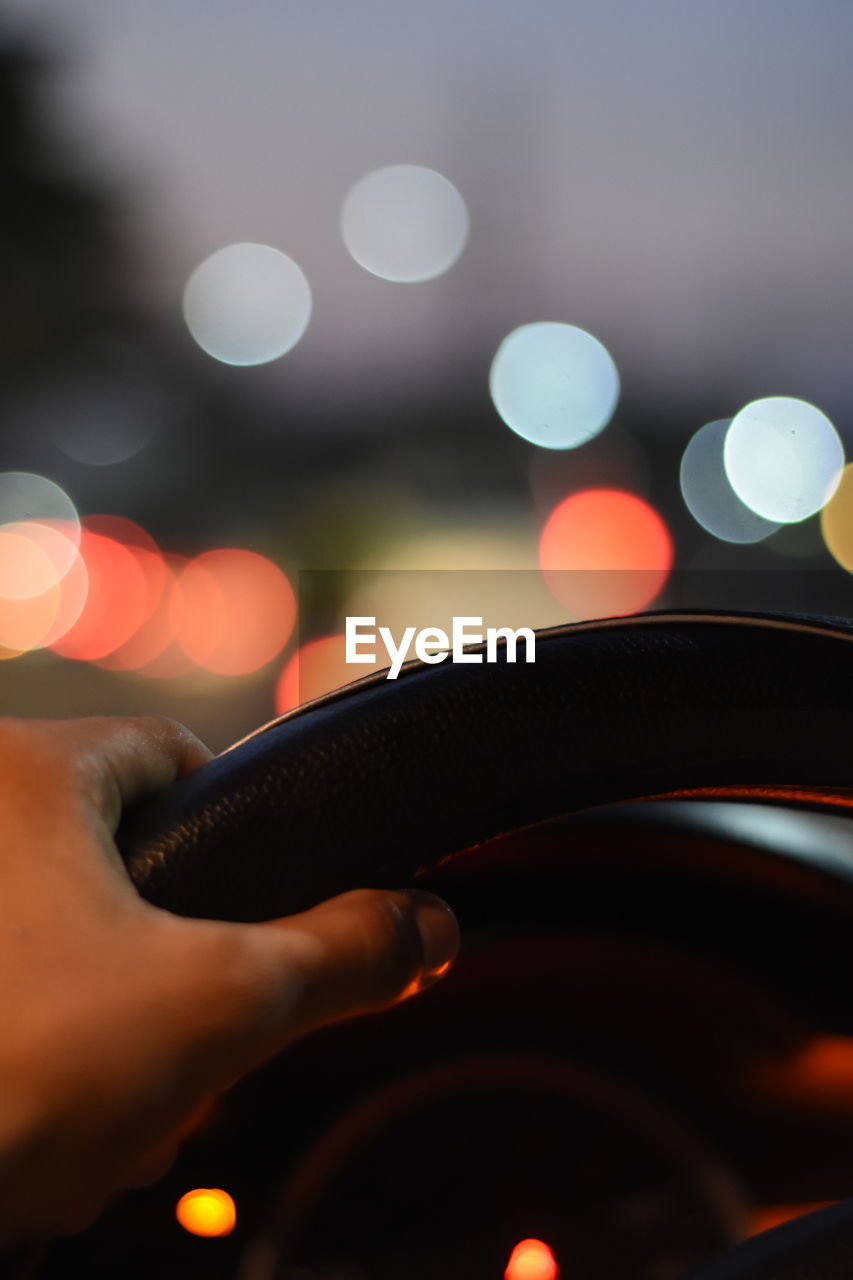 Close-up of human hand in car at night