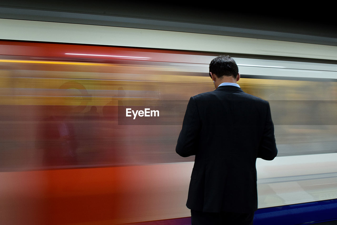 Rear view of man standing at railroad station platform