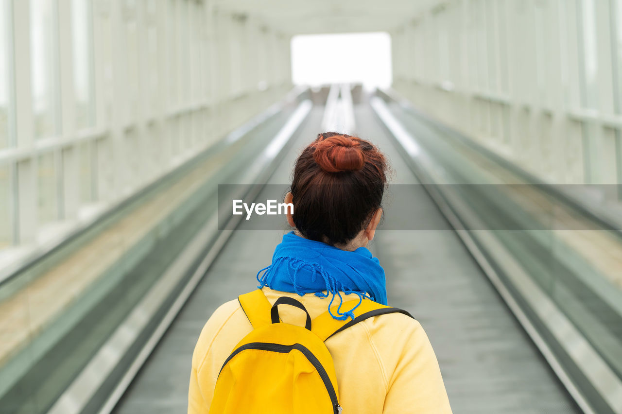 Rear view of woman with umbrella standing on railway station