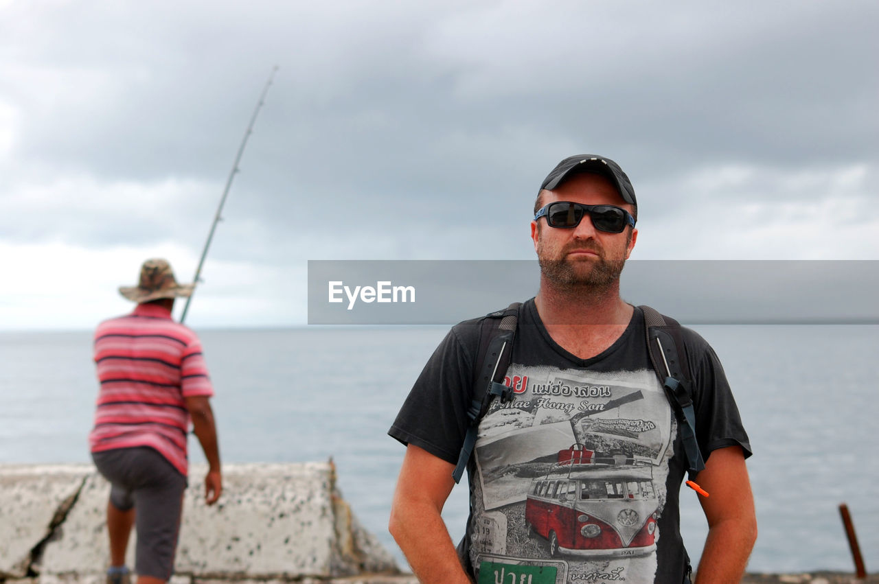 Portrait of man with friend standing at beach