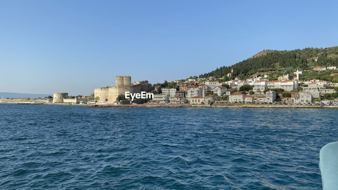 Sea by buildings against clear blue sky