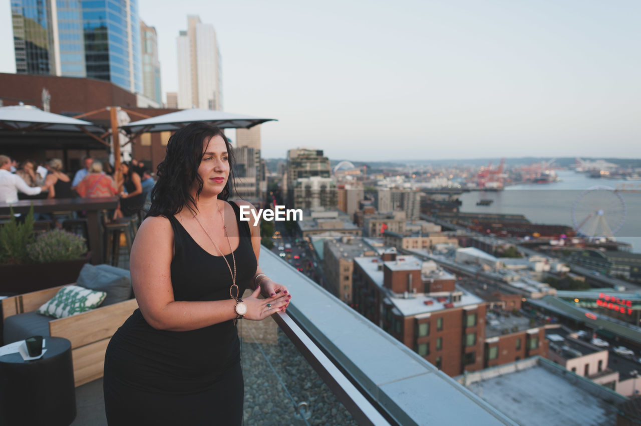 Young woman standing at terrace restaurant in city