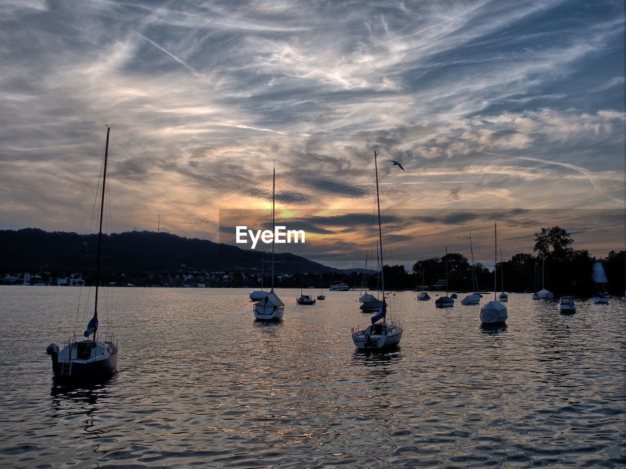 Boats in river against sky during sunset