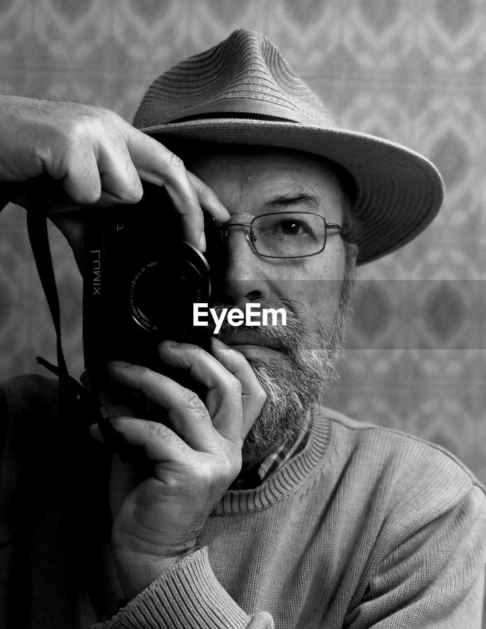 Senior man wearing hat photographing by camera