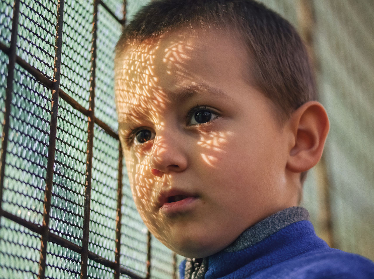 Close-up of boy by fence