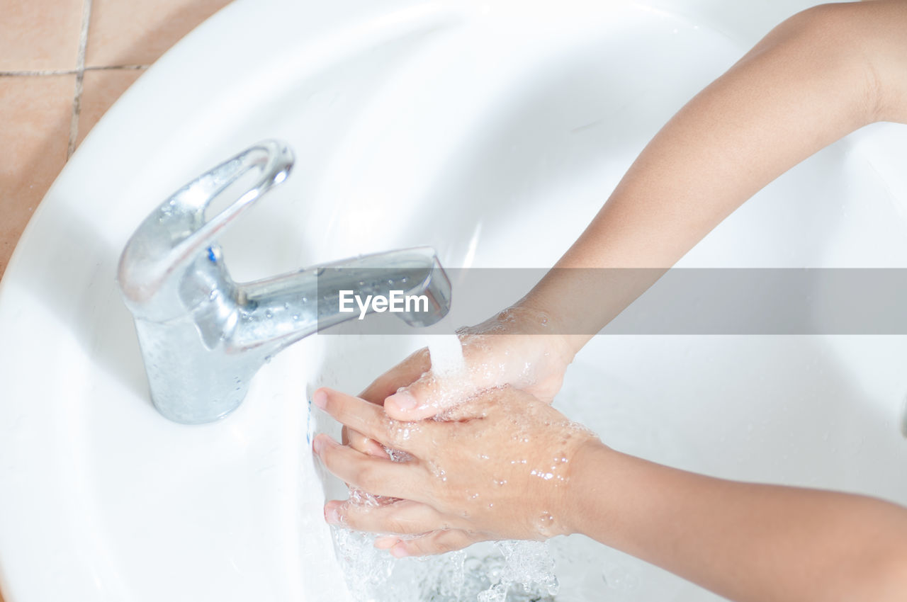 Close-up of person washing hands under faucet