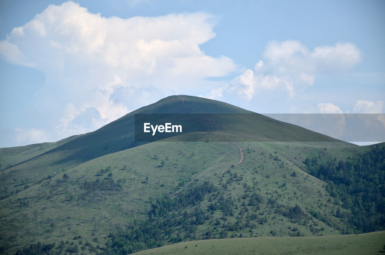 Mountain with a path beneath blue sky