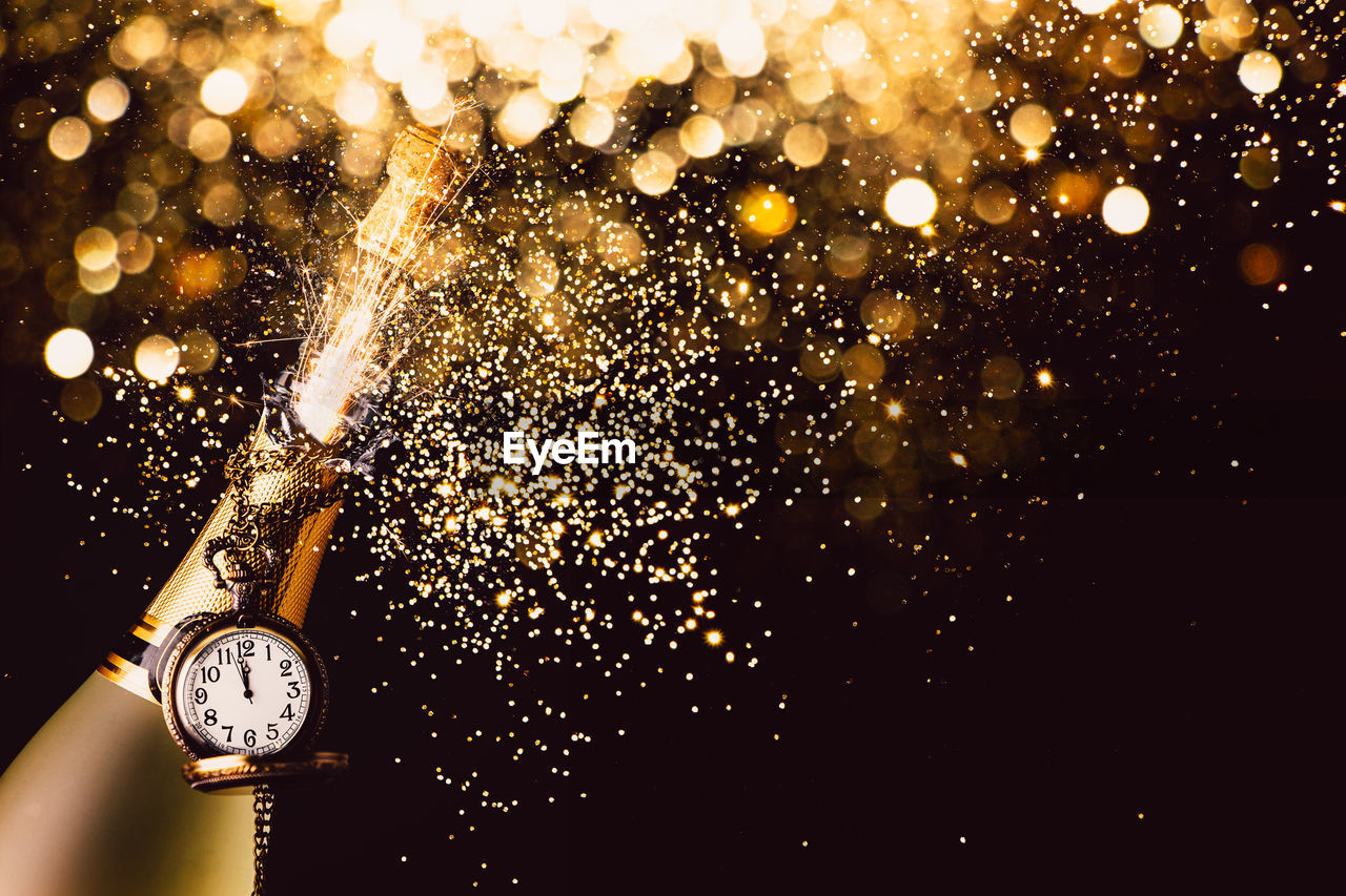 Close-up of champagne with pocket watch against black background