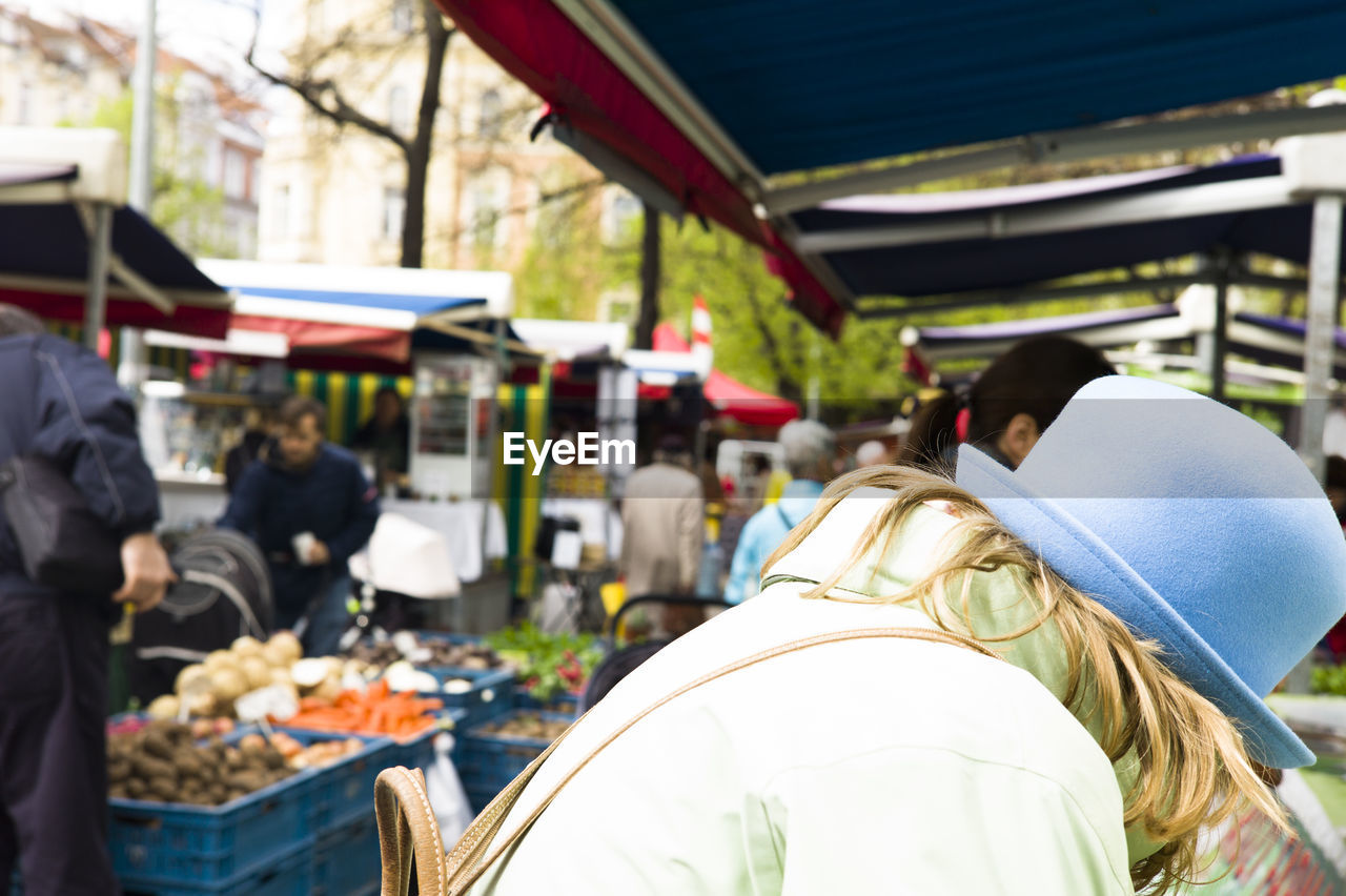 REAR VIEW OF PEOPLE AT MARKET STALL