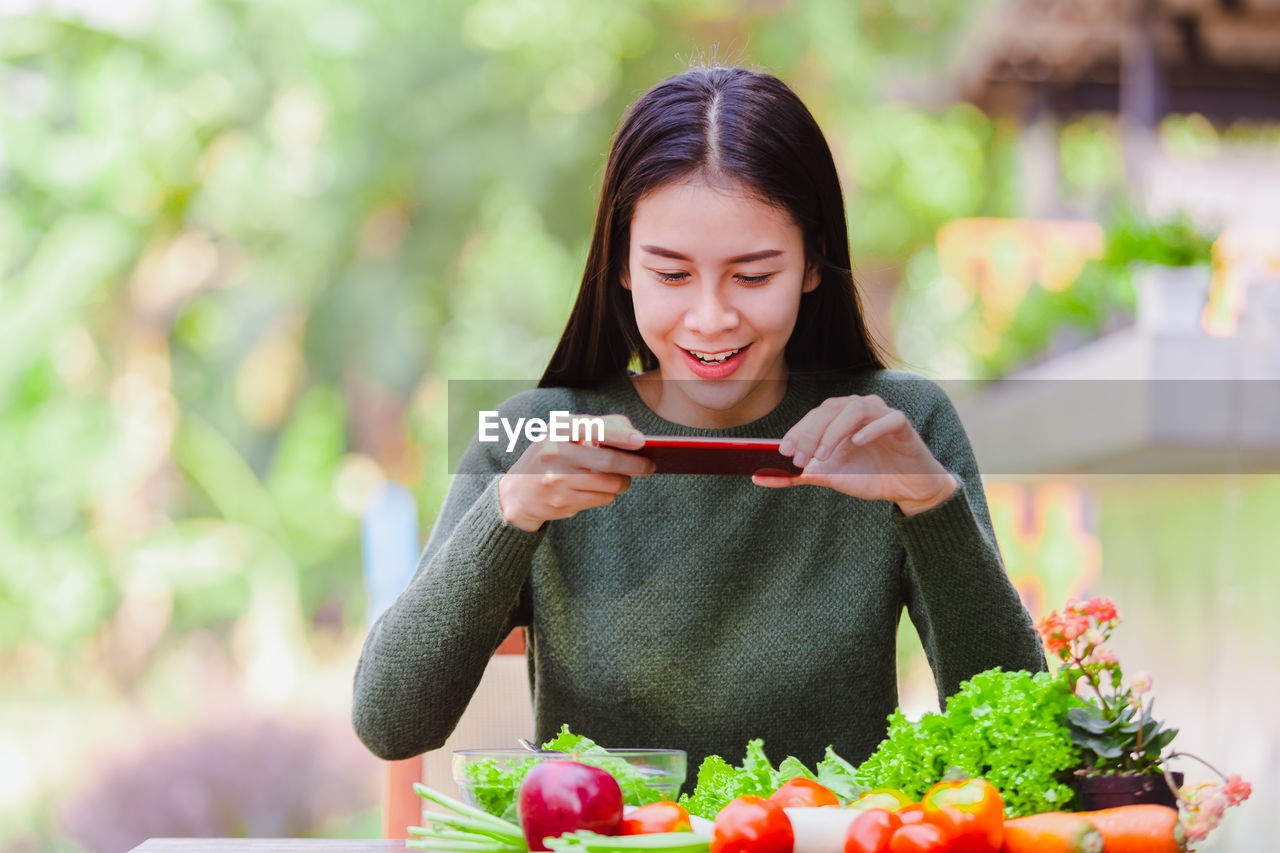 Young woman photographing salad from mobile phone at outdoor restaurant