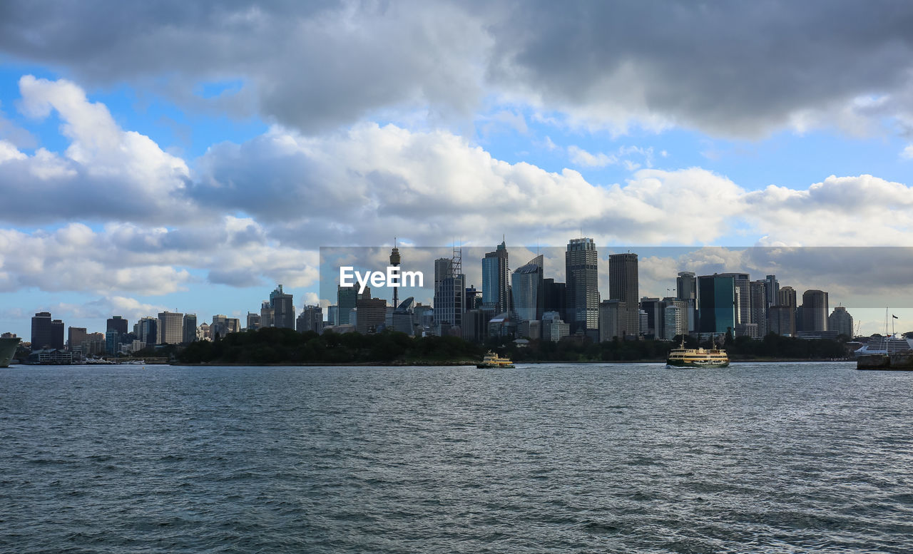 Sea by modern buildings against sky in city