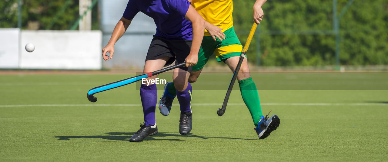 Low section of men playing hockey on turf