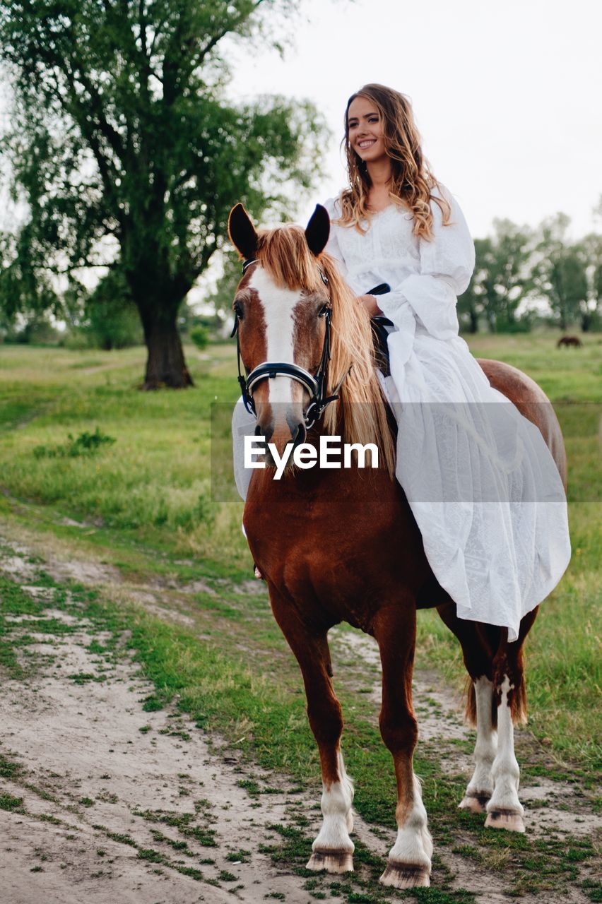 Young woman riding horse on field