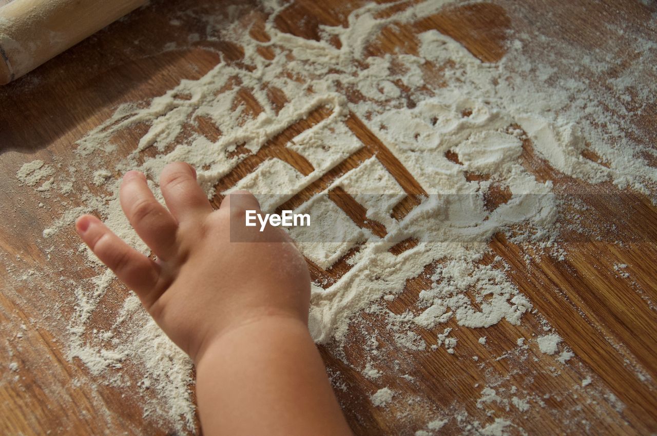 Cropped hands of girl playing with flour on table