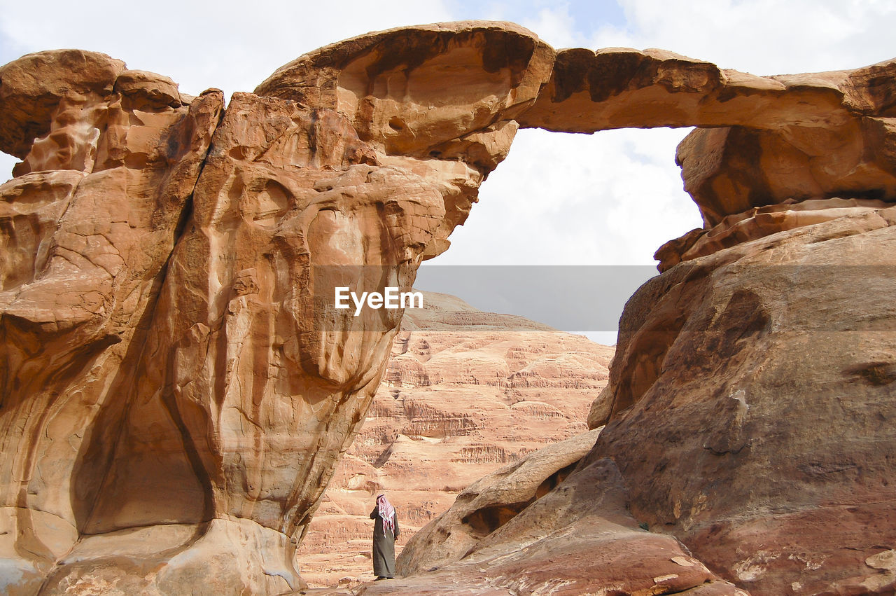 Rear view of man wearing traditional clothing standing on rock formations