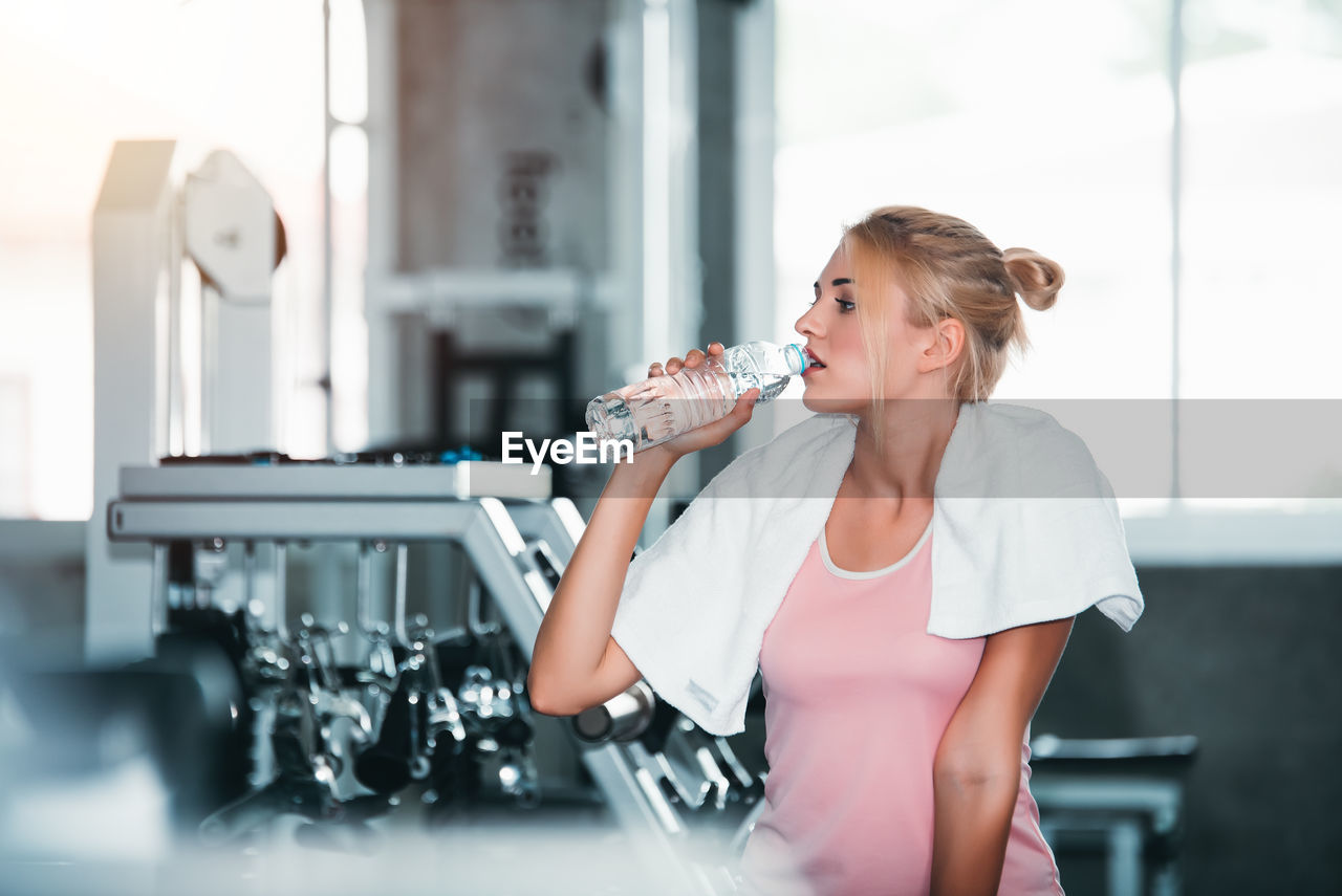 Young woman drinking water in gym
