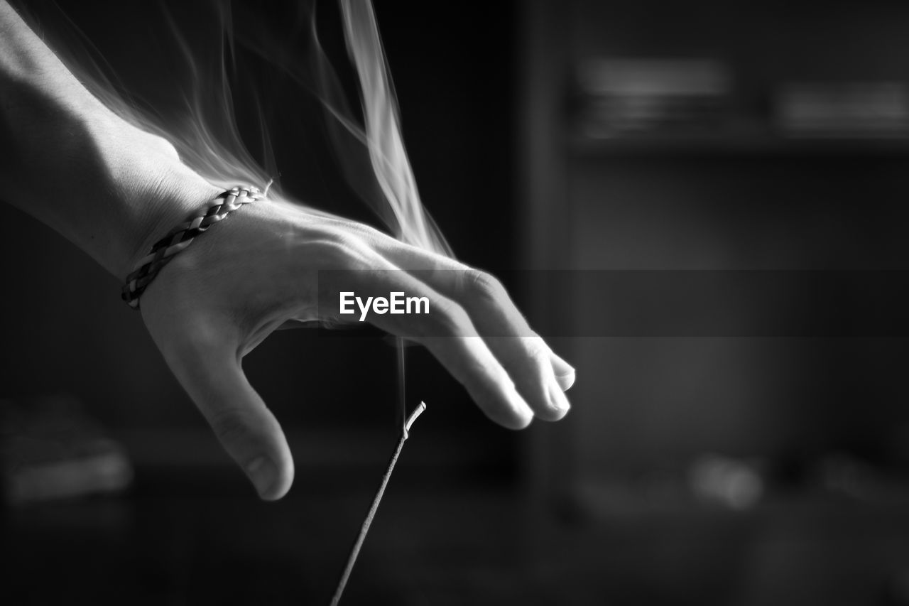 Cropped hand of woman over burning incense