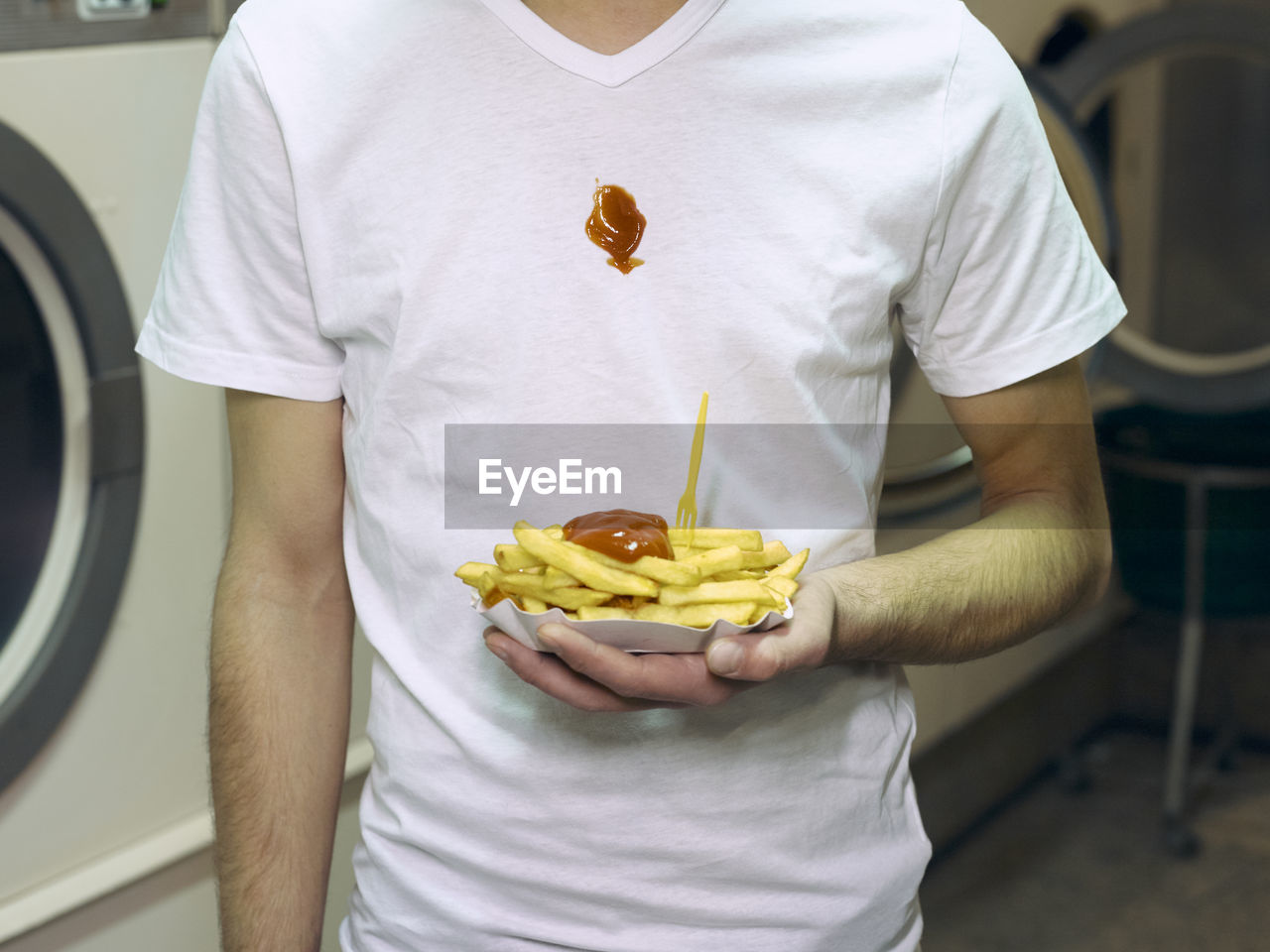 Midsection of man holding french fries in paper plate