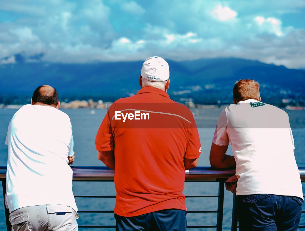 REAR VIEW OF PEOPLE STANDING IN FRONT OF RIVER