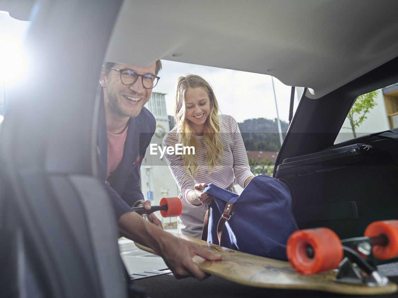 Smiling couple loading boot of electric car