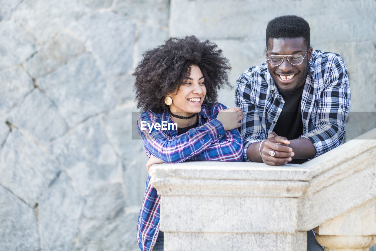 Smiling young couple talking while standing by railing