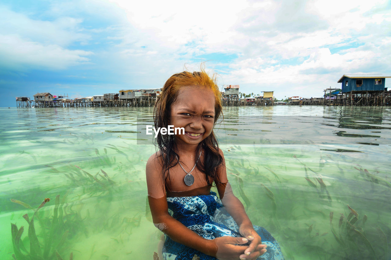 PORTRAIT OF SMILING WOMAN STANDING IN WATER