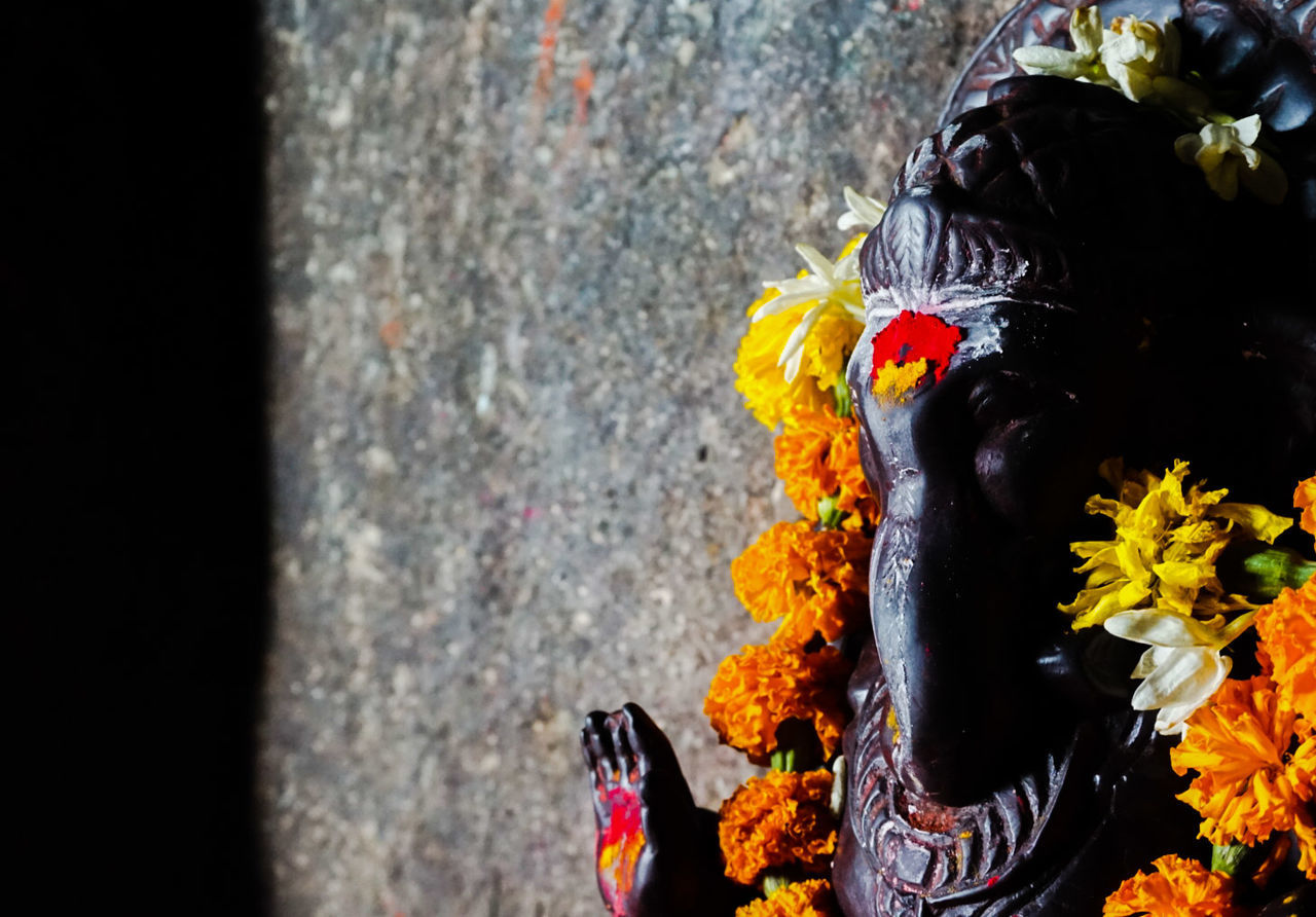 Floral garland on ganesha statue by wall