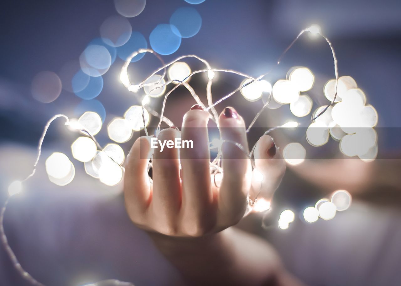 Close-up of woman's hand holding fairy lights