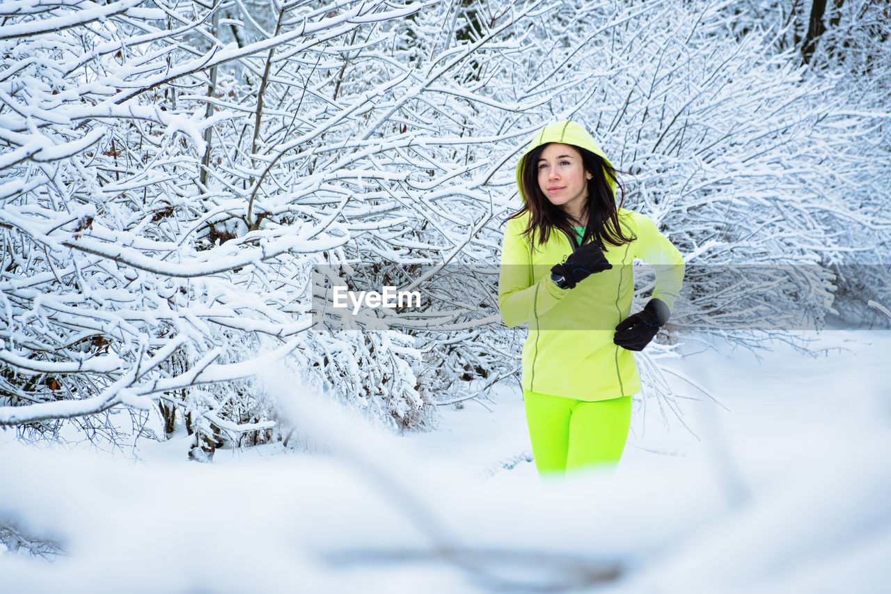 Cold weather running. happy woman running in winter snowy park, forest. running athlete woman