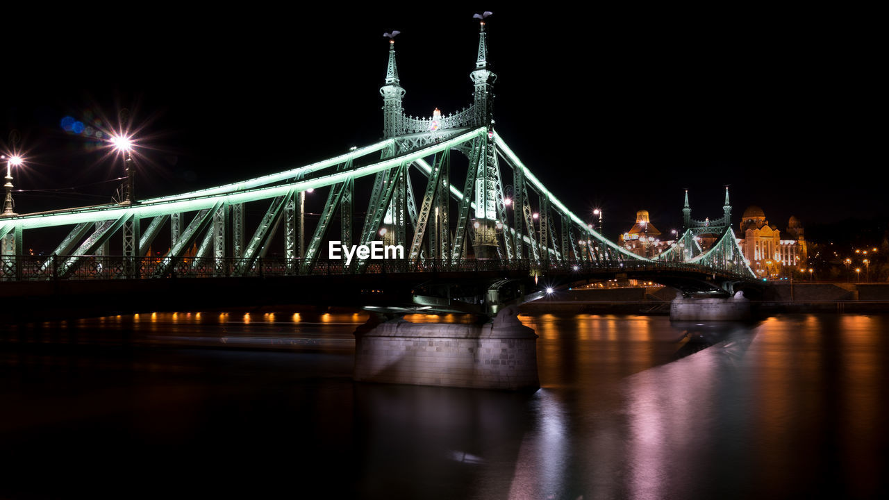 Illuminated suspension bridge over river at night