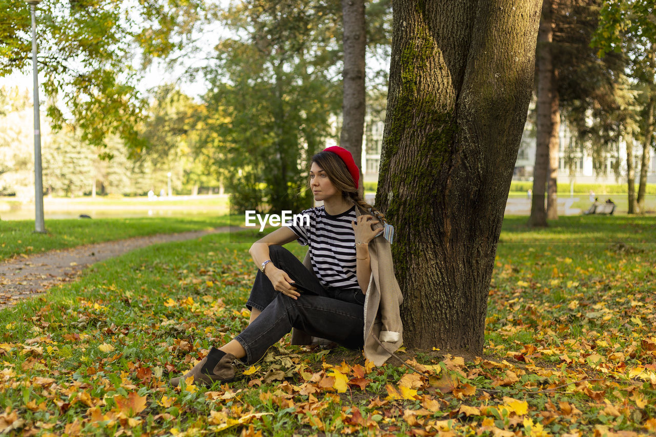 A woman under a tree, dressed in french style.