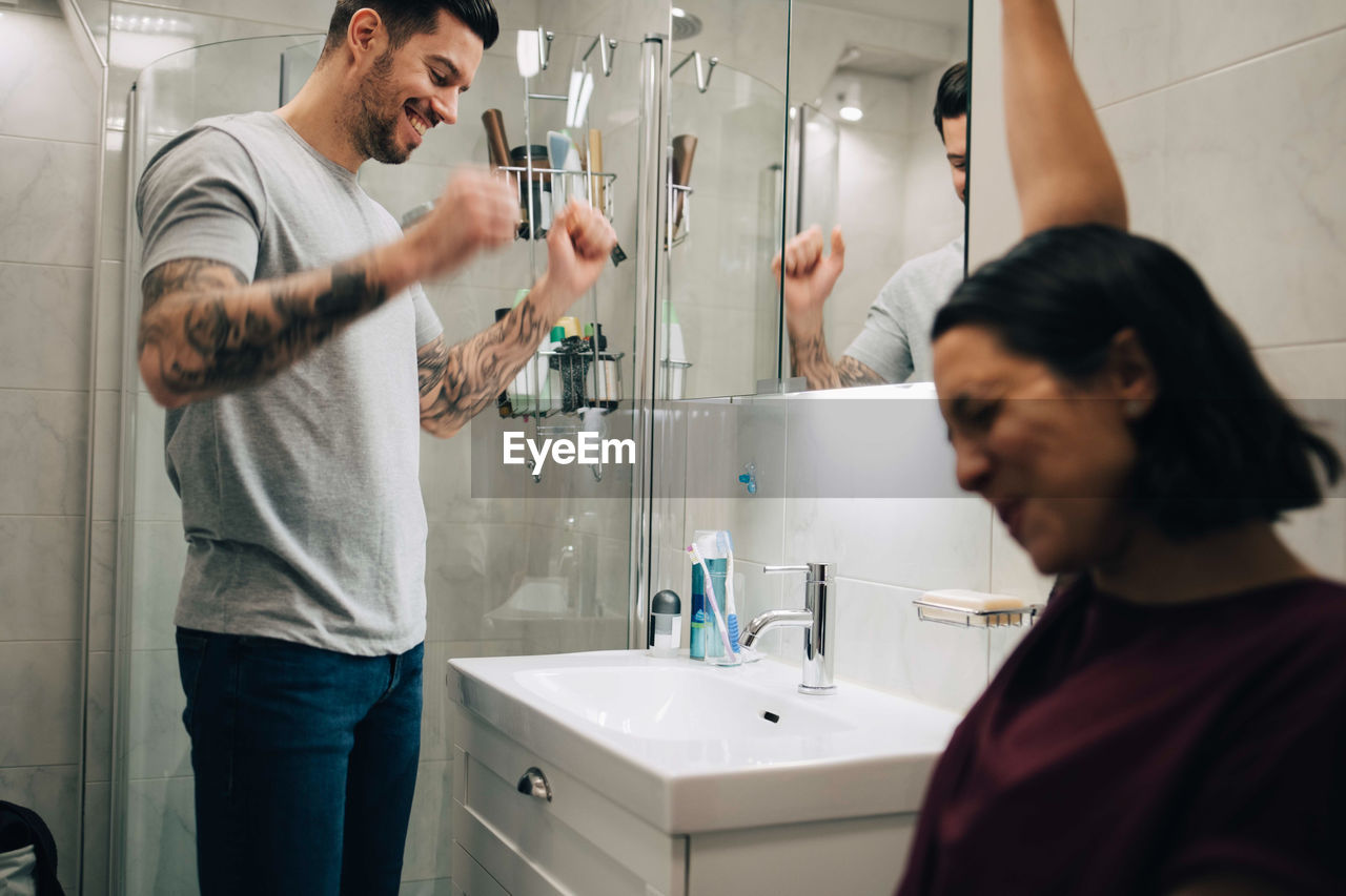 Cheerful couple by sink in bathroom at new home