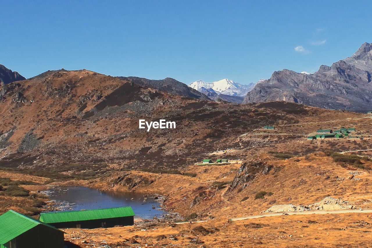 mountain, environment, landscape, scenics - nature, mountain range, nature, sky, land, beauty in nature, wilderness, no people, valley, travel destinations, geology, blue, water, day, travel, outdoors, clear sky, lake, non-urban scene, tranquility, plateau, tranquil scene, sunny, rock, activity, natural environment, architecture