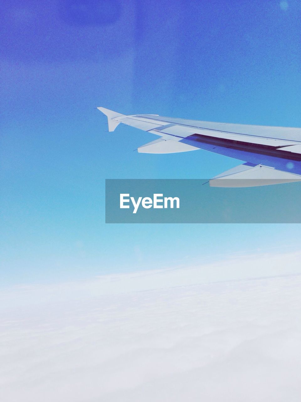 Cropped image of airplane over cloudscape against clear blue sky