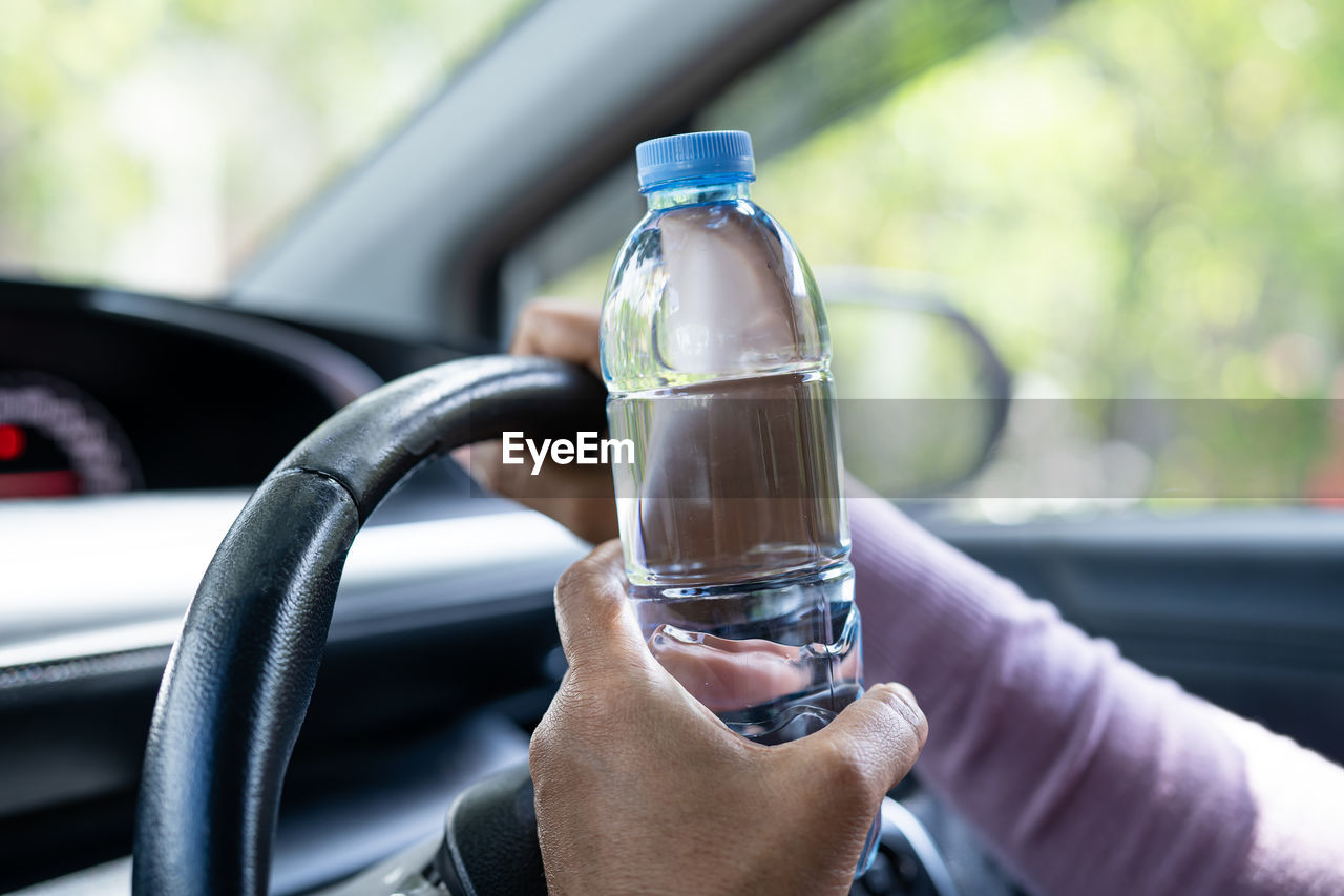 cropped hand of man holding drink in car