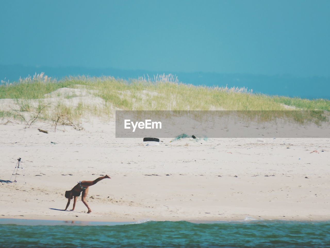 Mid distance view of playful woman practicing cartwheel at beach