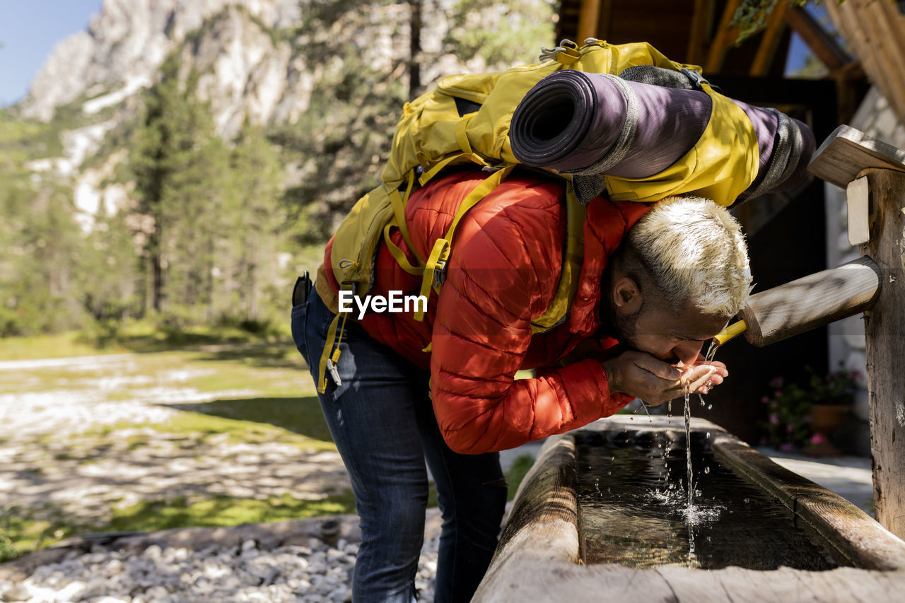 Hiker with backpack drinking water from fountain