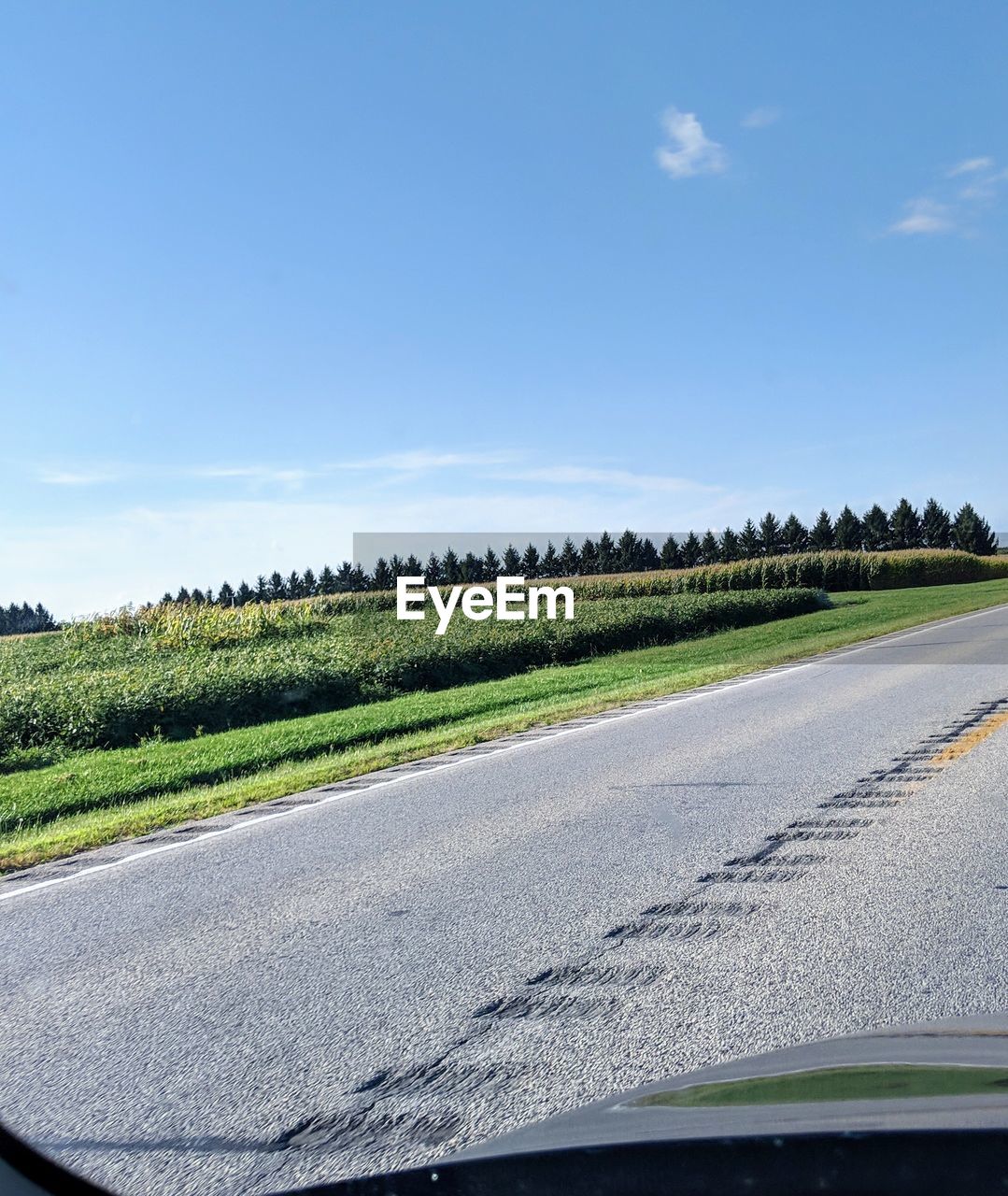 COUNTRY ROAD AGAINST SKY SEEN FROM CAR WINDSHIELD