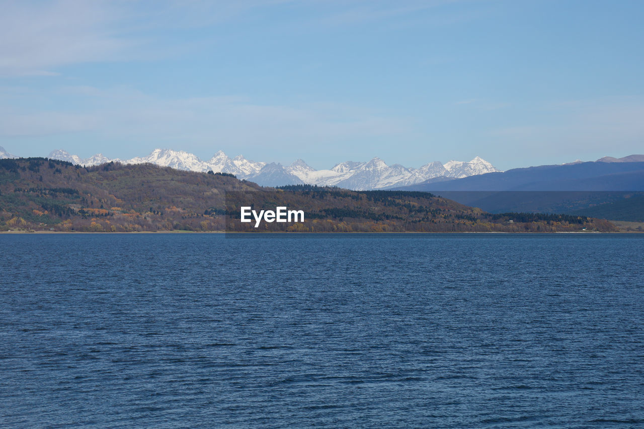 SCENIC VIEW OF SEA AND MOUNTAINS AGAINST BLUE SKY