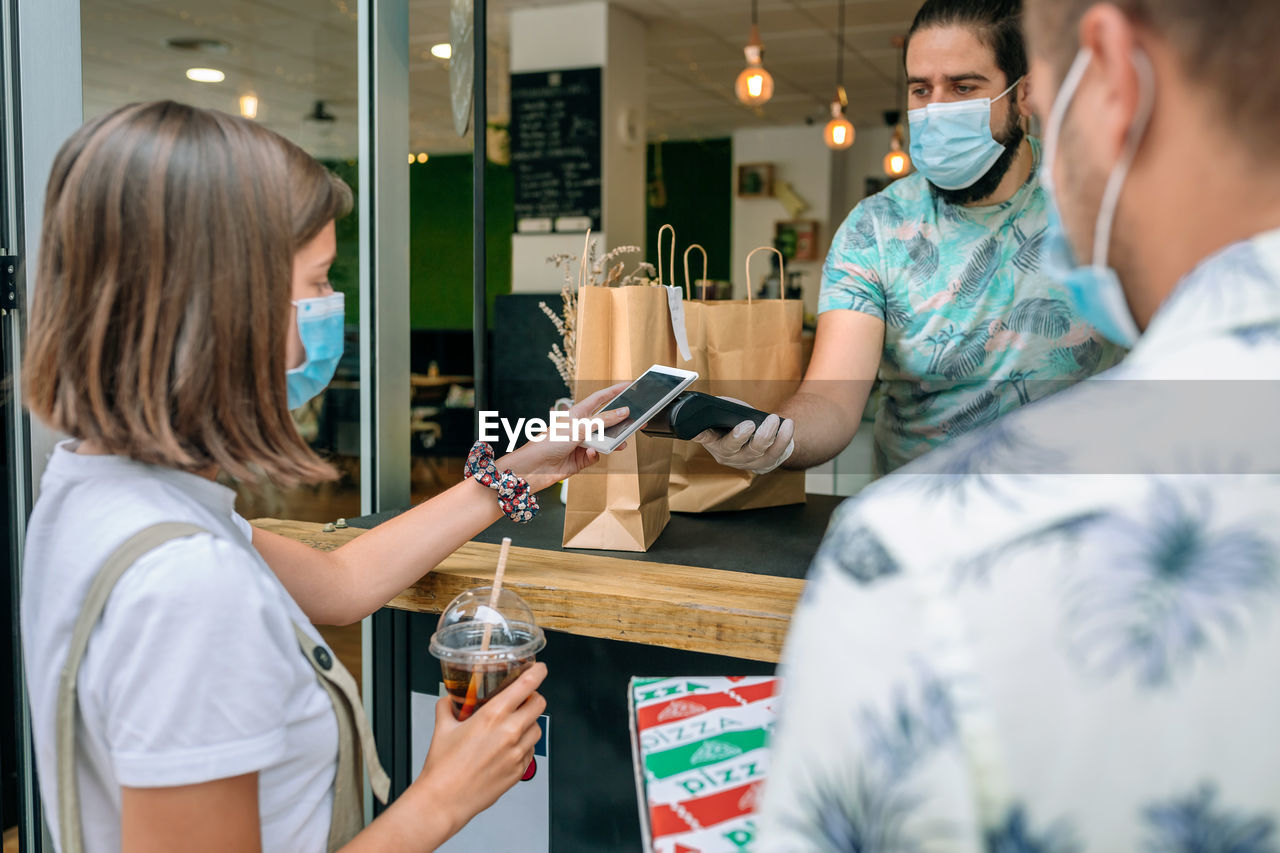 Woman making contactless payment through smart phone at restaurant