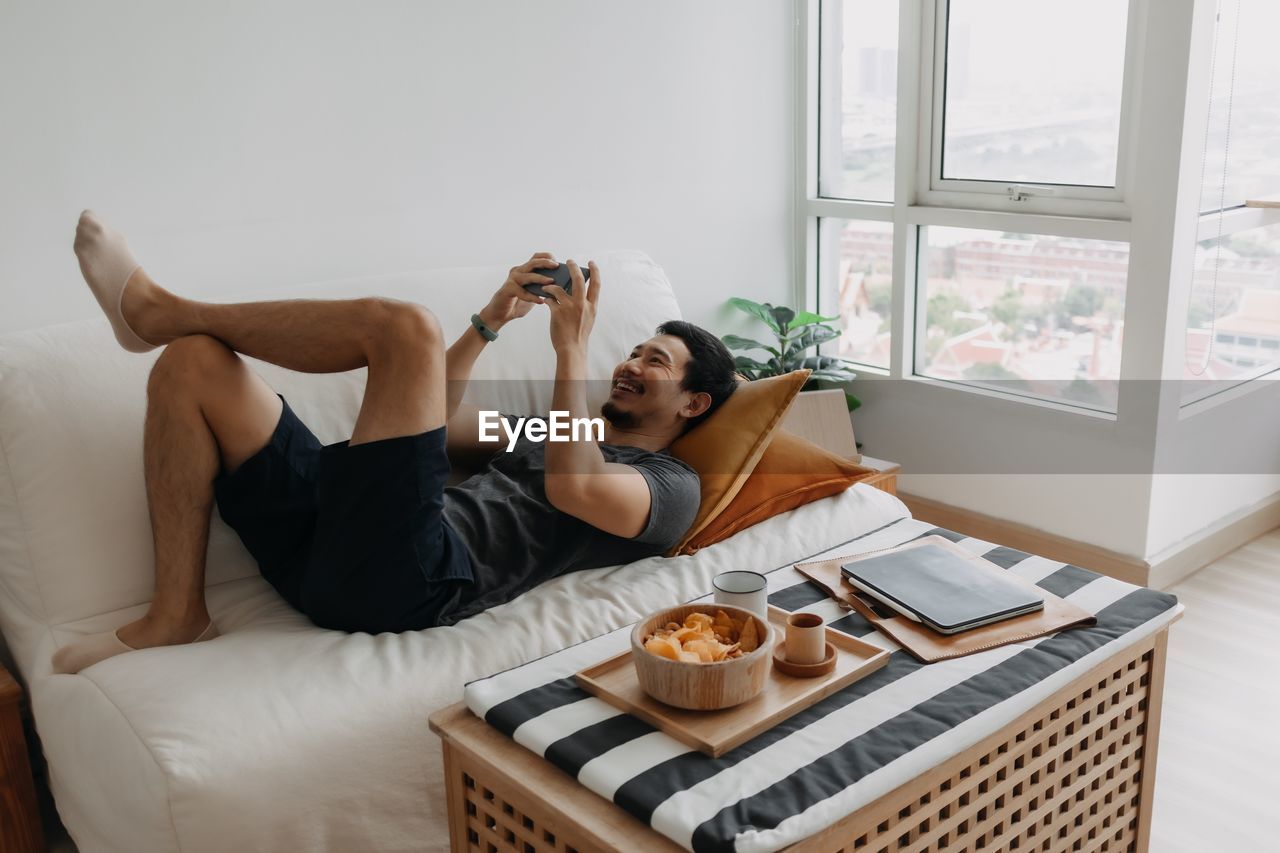 portrait of woman using digital tablet while sitting on bed at home