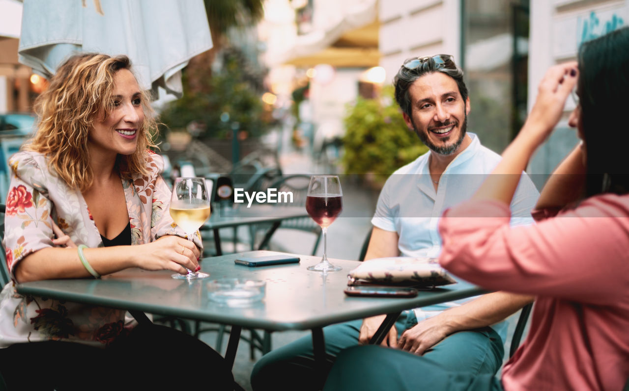 Friends having wine at table in restaurant