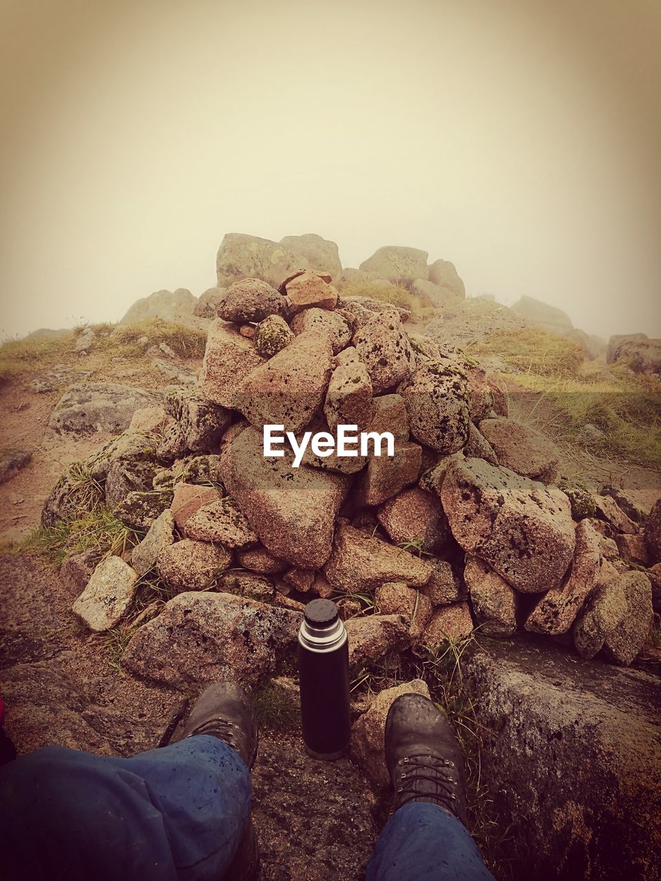 Low section of man on rock against sky