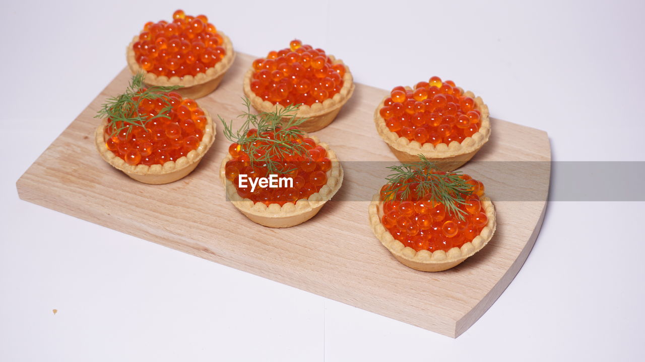Red caviar served on cutting board against white background