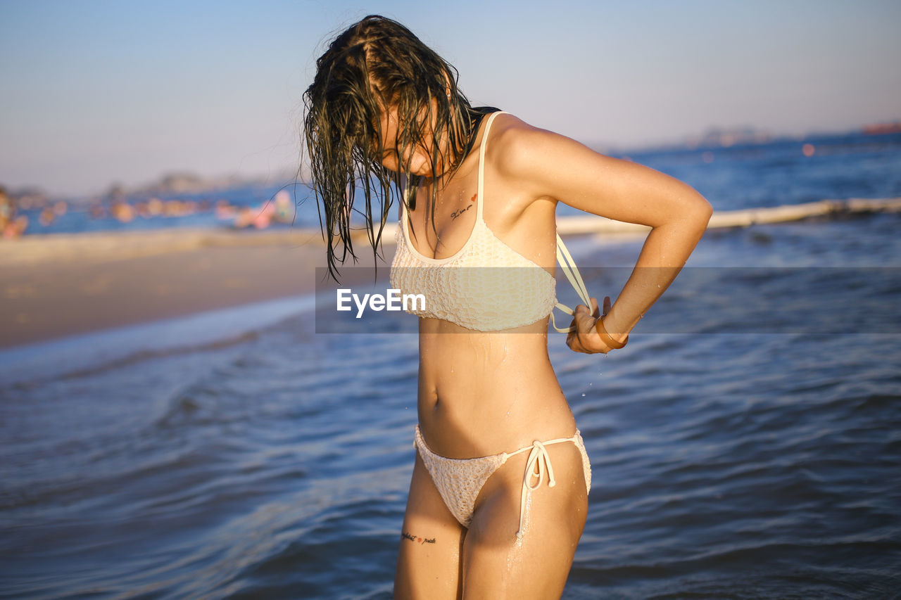 water, adult, clothing, women, one person, swimwear, sea, bikini, young adult, vacation, trip, summer, holiday, land, beach, hairstyle, nature, long hair, relaxation, sky, lifestyles, leisure activity, female, rear view, photo shoot, beauty in nature, sunlight, fashion, focus on foreground, travel, three quarter length, standing, outdoors, brown hair, sun tanning, limb, swimsuit top, day, sunset, sun, motion, enjoyment, travel destinations, wellbeing, emotion, copy space, human leg, environment, human hair, lingerie, carefree, happiness, portrait, tranquility