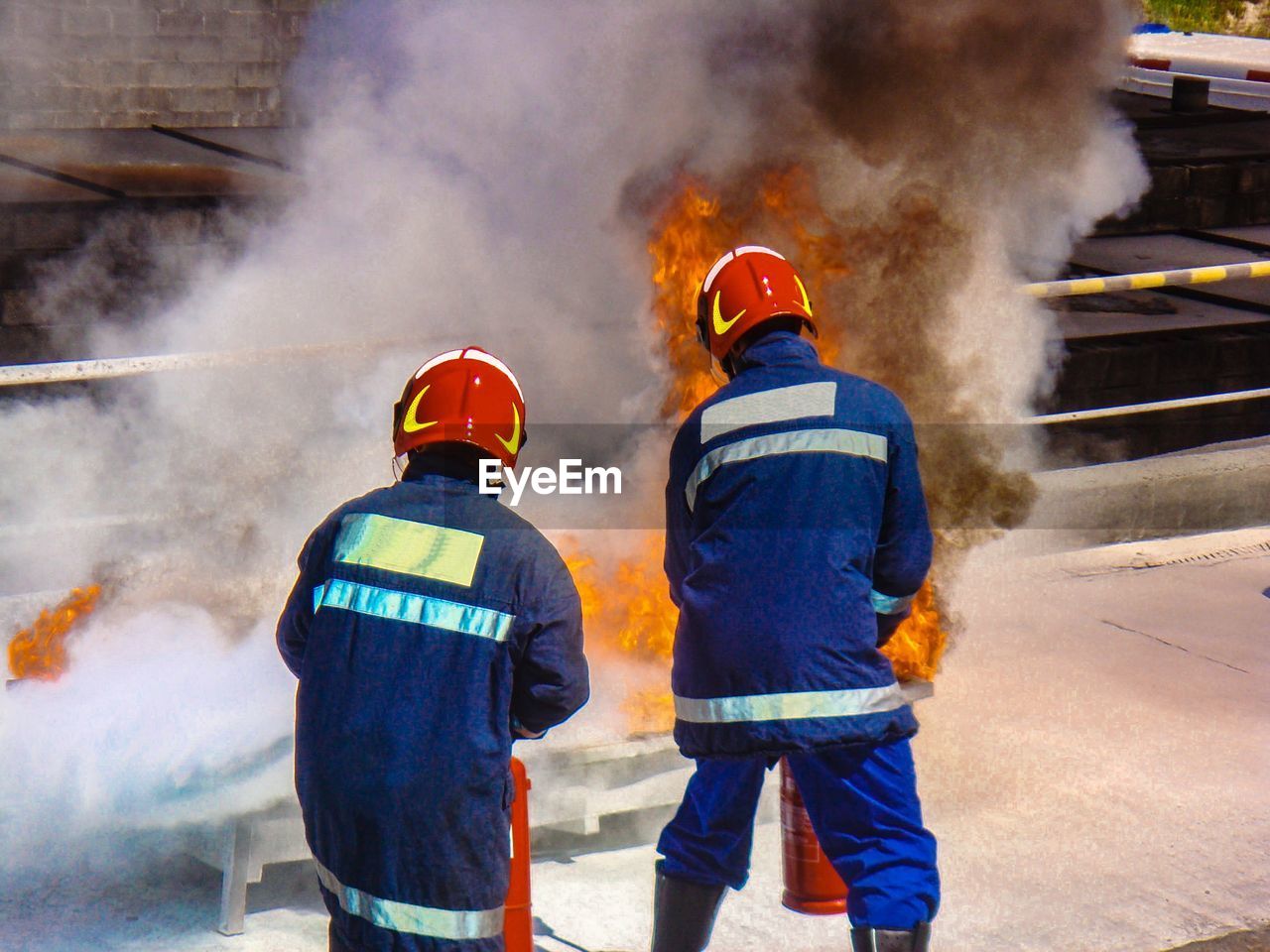 Rear view of firefighters extinguish fire on bridge