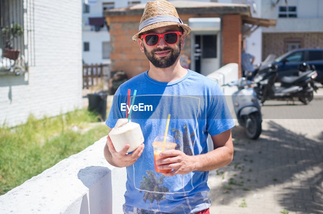 Smiling man holding coconut water on walkway